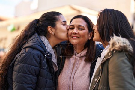 Photo for Three woman mother and daughters standing together and kissing at street - Royalty Free Image