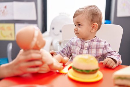 Photo for Adorable caucasian boy playing with baby doll and food toy at kindergarten - Royalty Free Image