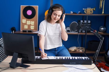 Téléchargez les photos : Young woman musician composing song at music studio - en image libre de droit
