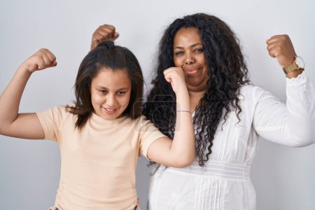 Téléchargez les photos : Mère et jeune fille debout sur fond blanc montrant les muscles des bras souriant fiers. concept de fitness. - en image libre de droit