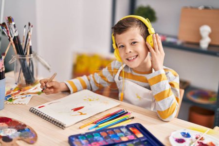 Téléchargez les photos : Enfant blond écoutant de la musique au studio d'art - en image libre de droit