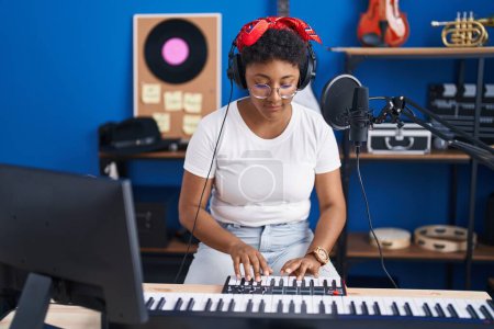 Foto de African american woman musician playing piano at music studio - Imagen libre de derechos
