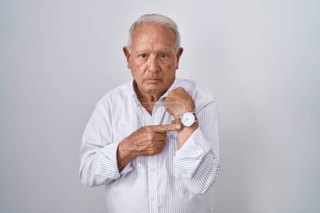 Photo for Senior man with grey hair standing over isolated background in hurry pointing to watch time, impatience, looking at the camera with relaxed expression - Royalty Free Image