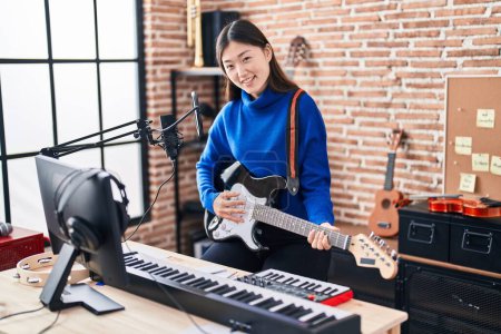 Téléchargez les photos : Femme artiste chinoise chantant chanson jouant de la guitare électrique au studio de musique - en image libre de droit