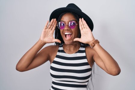 Photo for Young african american with braids wearing hat and sunglasses smiling cheerful playing peek a boo with hands showing face. surprised and exited - Royalty Free Image