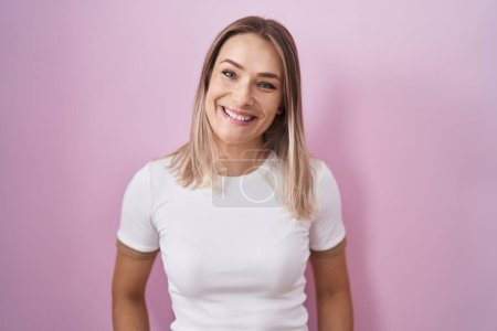 Photo for Blonde caucasian woman standing over pink background with a happy and cool smile on face. lucky person. - Royalty Free Image