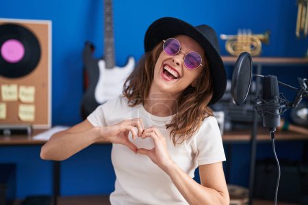 Téléchargez les photos : Jeune artiste femme faisant geste de cœur avec les mains au studio de musique - en image libre de droit