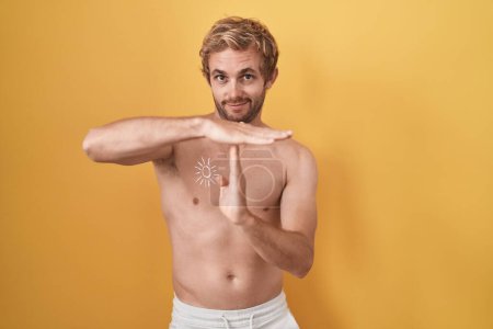 Photo for Caucasian man standing shirtless wearing sun screen doing time out gesture with hands, frustrated and serious face - Royalty Free Image