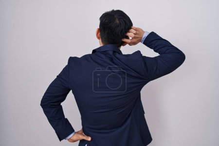 Foto de Joven asiático con traje de negocios y corbata al revés pensando en la duda con la mano en la cabeza - Imagen libre de derechos