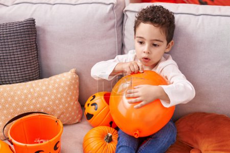 Foto de Adorable chico hispano teniendo fiesta de halloween sosteniendo globo en casa - Imagen libre de derechos