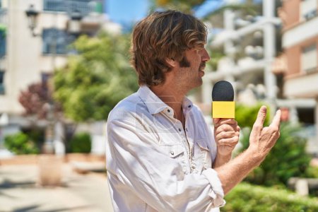 Téléchargez les photos : Jeune homme journaliste travaillant au microphone au parc - en image libre de droit