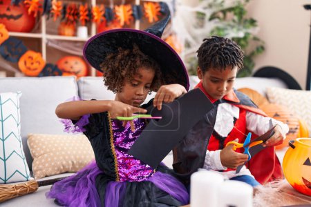 Foto de Adorable afroamericano chico y chica teniendo fiesta de Halloween corte de papel en casa - Imagen libre de derechos