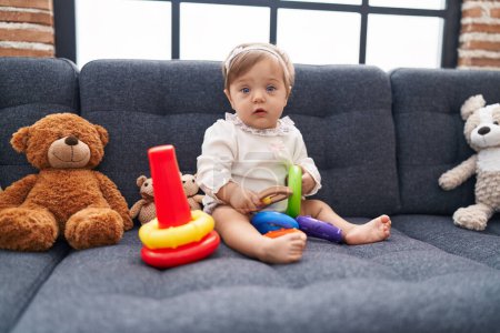 Téléchargez les photos : Adorable bébé caucasien jouant avec cerceaux jeu assis sur le canapé à la maison - en image libre de droit