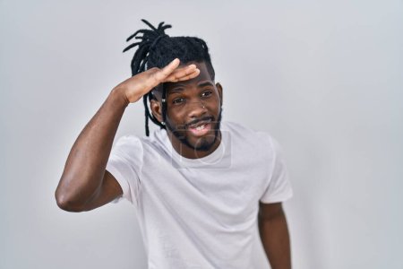 Photo for African man with dreadlocks wearing casual t shirt over white background very happy and smiling looking far away with hand over head. searching concept. - Royalty Free Image