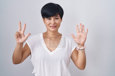 Photo for Young asian woman with short hair standing over isolated background showing and pointing up with fingers number eight while smiling confident and happy. - Royalty Free Image