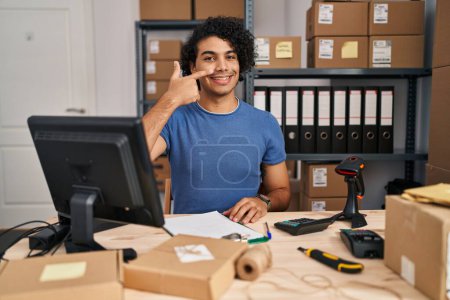 Foto de Hombre hispano con el pelo rizado que trabaja en el comercio electrónico de la pequeña empresa señalando con el dedo a la mano y la nariz, sonriendo alegre. concepto de belleza - Imagen libre de derechos