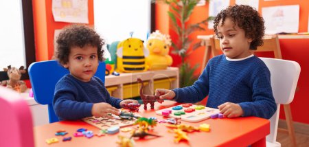 Photo for Adorable african american boys playing with maths puzzle game and dinosaur toy at kindergarten - Royalty Free Image