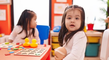 Téléchargez les photos : Adorables filles jumelles jouant avec des mathématiques jeu de puzzle assis sur la table à la maternelle - en image libre de droit