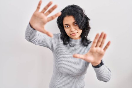 Téléchargez les photos : Femme hispanique avec les cheveux foncés debout sur fond isolé faisant cadre à l'aide de mains paumes et doigts, perspective de la caméra - en image libre de droit