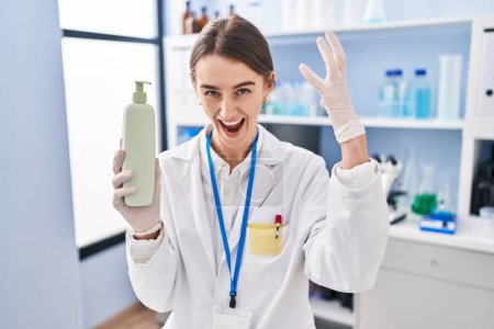 Photo for Young caucasian woman working at scientist laboratory holding body lotion annoyed and frustrated shouting with anger, yelling crazy with anger and hand raised - Royalty Free Image