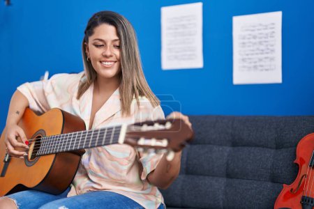 Foto de Joven músico hispano tocando la guitarra clásica en el estudio de música - Imagen libre de derechos