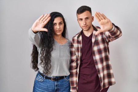 Photo for Young hispanic couple standing over white background doing frame using hands palms and fingers, camera perspective - Royalty Free Image