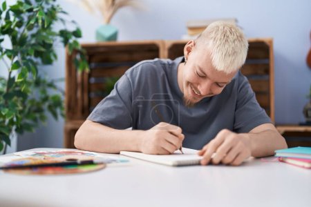 Téléchargez les photos : Jeune homme caucasien souriant dessin confiant sur ordinateur portable à la maison - en image libre de droit