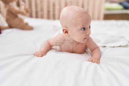 Foto de Adorable bebé caucásico acostado en la cama en el dormitorio - Imagen libre de derechos
