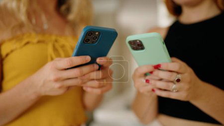 Photo for Two women using smartphone standing at home - Royalty Free Image