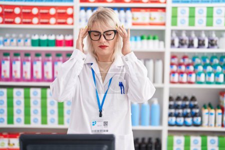 Photo for Young caucasian woman working at pharmacy drugstore with hand on head for pain in head because stress. suffering migraine. - Royalty Free Image