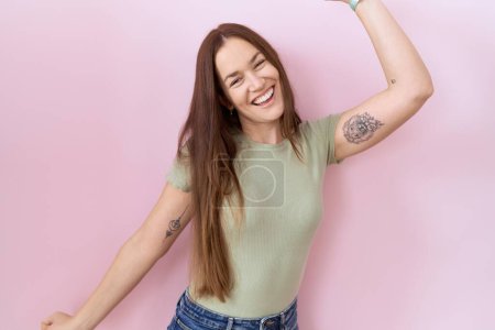 Téléchargez les photos : Belle femme brune debout sur fond rose dansant heureux et joyeux, souriant décontracté et confiant écoutant de la musique - en image libre de droit