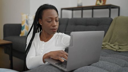 Foto de Mujer afroamericana usando portátil sentado en el suelo en casa - Imagen libre de derechos