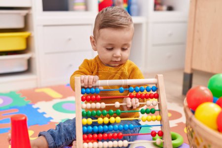 Photo for Adorable caucasian baby playing with abacus sitting on floor at kindergarten - Royalty Free Image