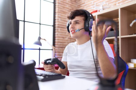Téléchargez les photos : Non binaire homme streamer jouer jeu vidéo en utilisant joystick à la salle de jeu - en image libre de droit