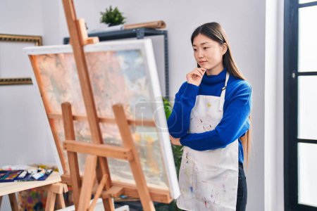 Photo for Chinese woman artist looking draw with doubt expression at art studio - Royalty Free Image