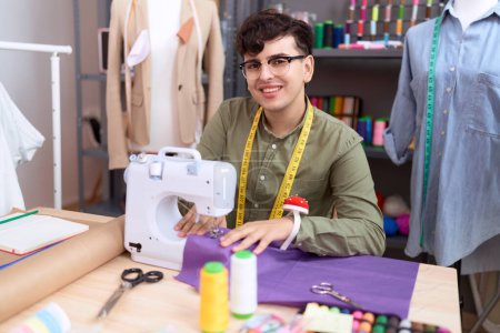 Foto de Non binary man tailor smiling confident using sewing machine at atelier - Imagen libre de derechos