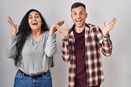 Téléchargez les photos : Jeune couple hispanique debout sur fond blanc célébrant fou et étonné pour le succès avec les bras levés et les yeux ouverts hurlant excités. concept gagnant - en image libre de droit