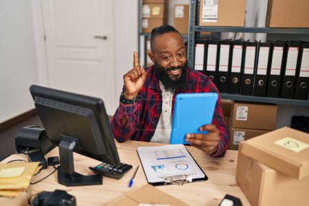 Foto de Hombre afroamericano que trabaja en el comercio electrónico de pequeñas empresas haciendo videollamadas sonriendo con una idea o pregunta señalando con el dedo con la cara feliz, número uno - Imagen libre de derechos