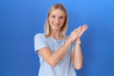 Téléchargez les photos : Jeune femme caucasienne portant casual t-shirt bleu applaudissements heureux et joyeux, souriant mains fières ensemble - en image libre de droit