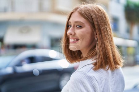 Téléchargez les photos : Jeune rousse femme souriant confiant debout à la rue - en image libre de droit