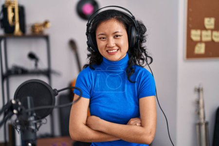 Photo for Young chinese woman singer smiling confident with arms crossed gesrture at music studio - Royalty Free Image