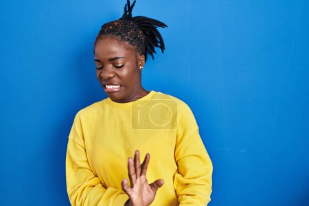 Téléchargez les photos : Beautiful black woman standing over blue background disgusted expression, displeased and fearful doing disgust face because aversion reaction. - en image libre de droit