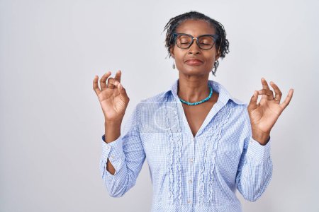 Photo for African woman with dreadlocks standing over white background wearing glasses relax and smiling with eyes closed doing meditation gesture with fingers. yoga concept. - Royalty Free Image
