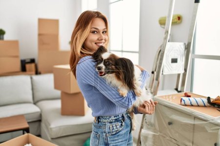 Photo for Young caucasian woman smiling confident hugging dog at new home - Royalty Free Image