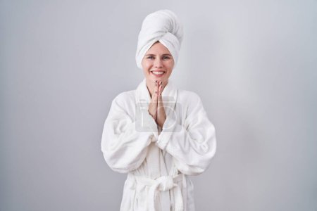 Photo for Blonde caucasian woman wearing bathrobe praying with hands together asking for forgiveness smiling confident. - Royalty Free Image