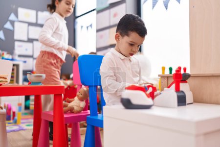 Téléchargez les photos : Adorable garçon et fille jouant jeu de supermarché assis sur la table à la maternelle - en image libre de droit