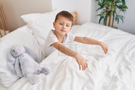 Photo for Adorable caucasian boy somnambulist sitting on bed at bedroom - Royalty Free Image