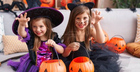 Foto de Adorables chicas teniendo fiesta de Halloween haciendo gesto de miedo en casa - Imagen libre de derechos