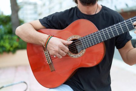 Foto de Joven músico hispano tocando guitarra clásica en el parque - Imagen libre de derechos