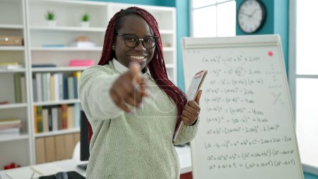Photo for African woman with braided hair teaching maths pointing to camera at university library - Royalty Free Image